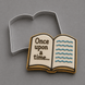 An open book-shaped cookie with white icing, brown lettering reading 'Once upon a time next to a 4.25 inch Open Book Metal Cookie Cutter