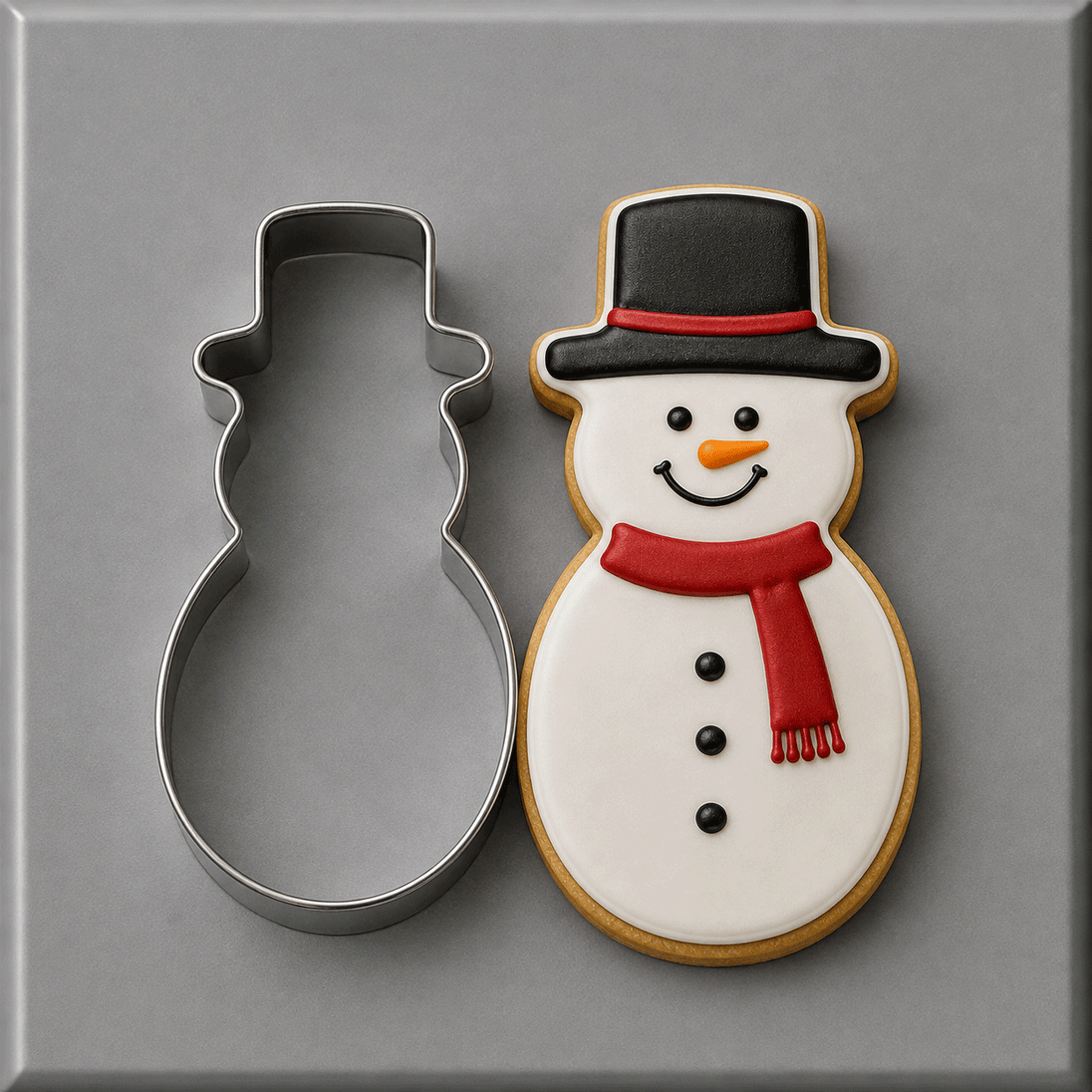 A 4.5 inch Snowman Metal Cookie Cutter shown next to a decorated snowman cookie on a smooth gray surface.